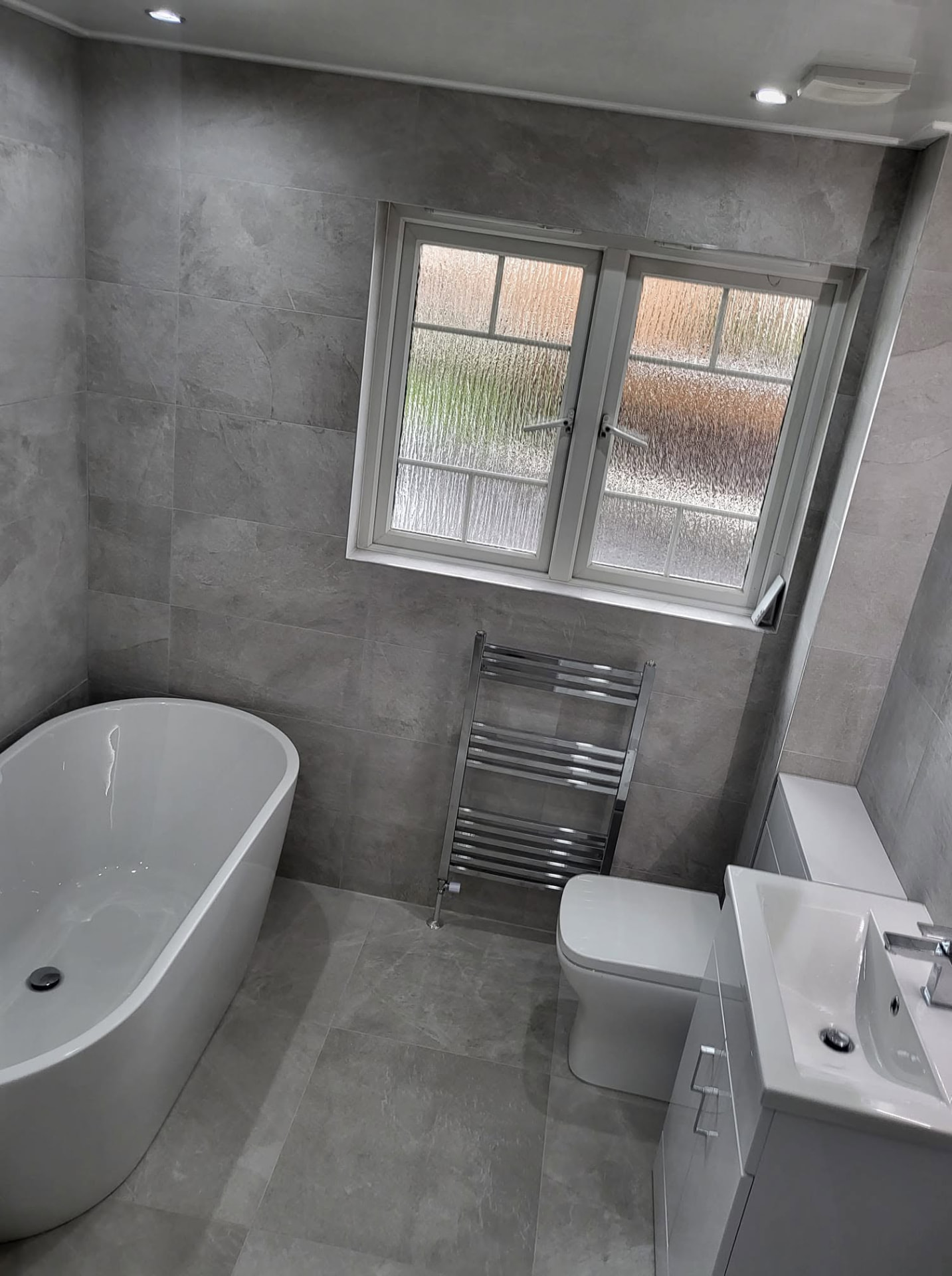 Modern grey tiled bathroom with freestanding bath fitted by Abbie Bathrooms